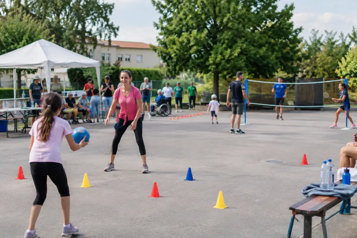 Ateliers sportifs variés dans une cour aménagée, avec matériel léger, zones de repos et participants de différents niveaux.