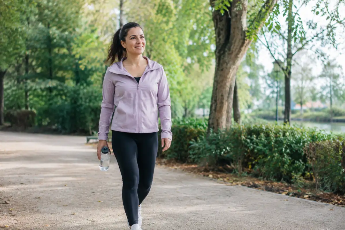 Adulte en tenue de sport marchant à son rythme dans un parc, illustration d’une activité physique adaptée à sa santé.