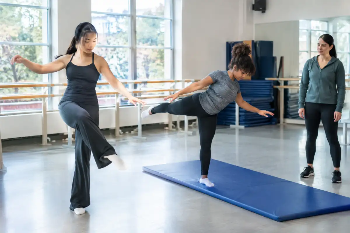 Débutants en danse et gymnastique répètent des mouvements simples dans un studio équipé de tapis et de barres.