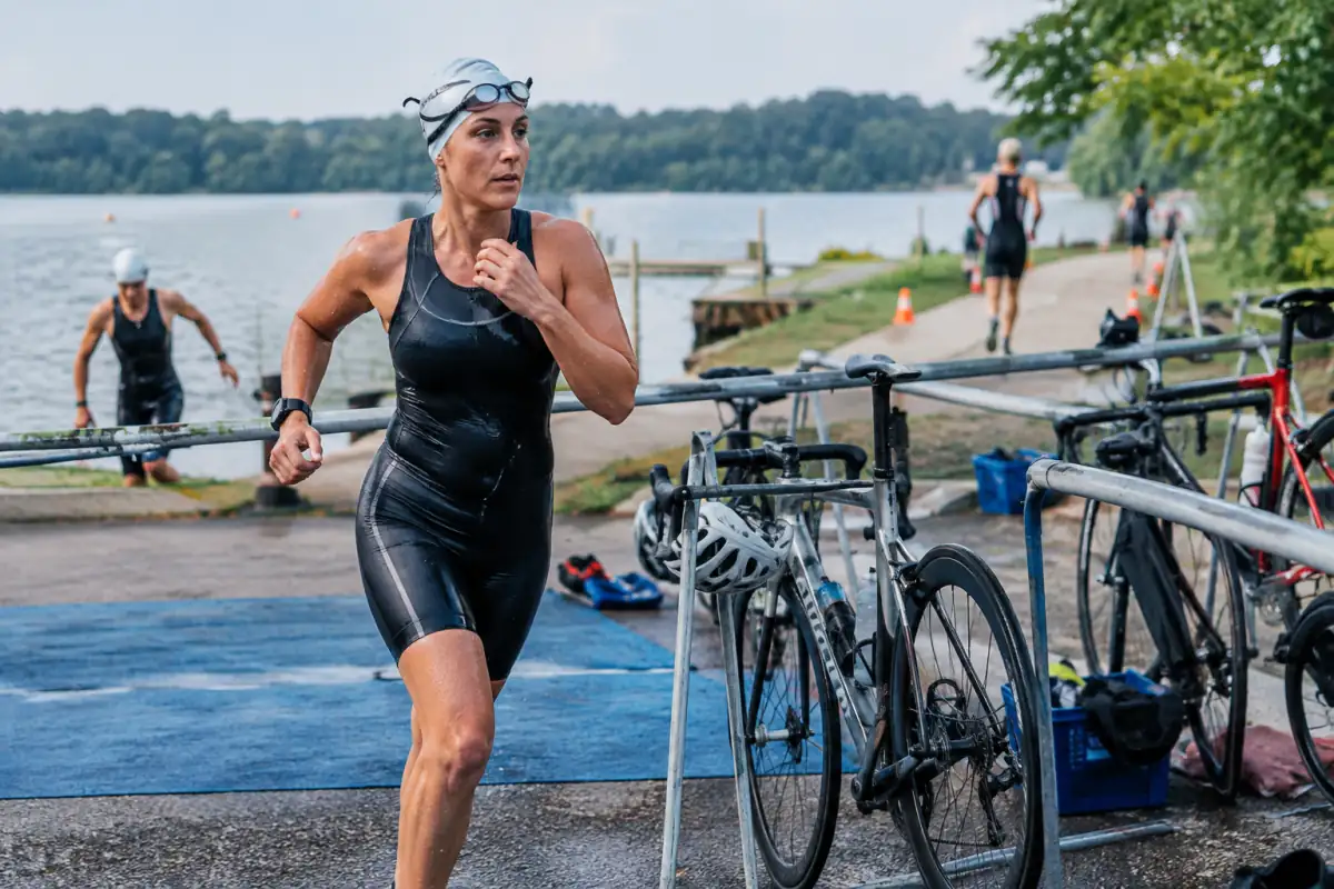 Épreuve multisport en plein air : un athlète sort de l’eau près d’un vélo et d’un parcours de course à pied.