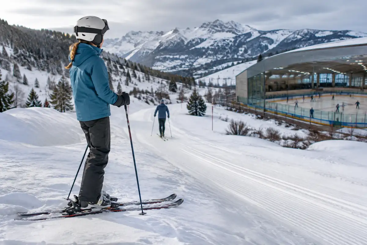 Skieur débutant sur une piste enneigée, avec des traces de ski de fond dans un paysage alpin hivernal.