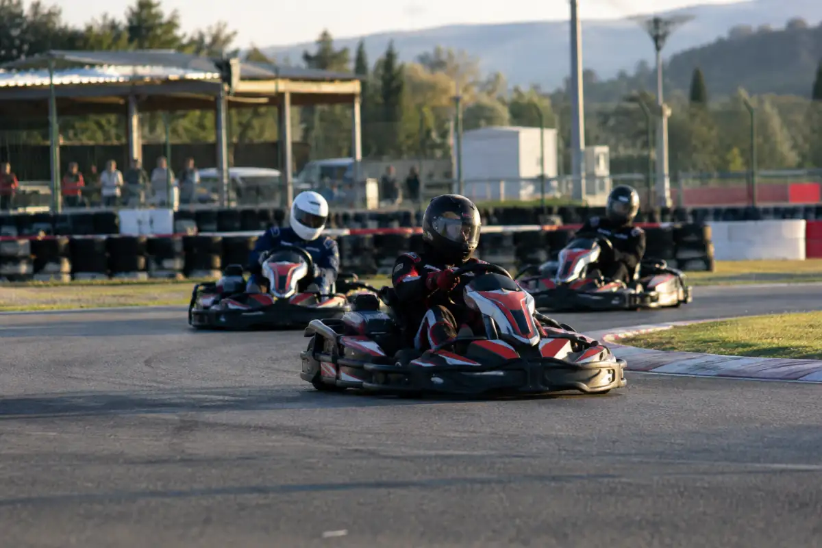Plusieurs karts pilotés et équipés de casques négocient un virage sur un circuit fermé, devant des barrières de sécurité.