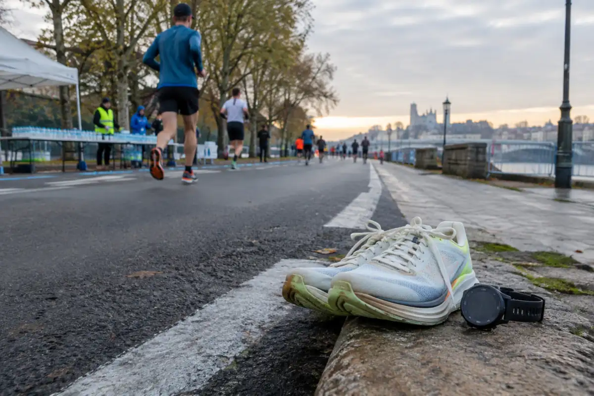 Chaussures de course et montre de sport au bord d’un parcours, évoquant l’estimation d’un temps de marathon.