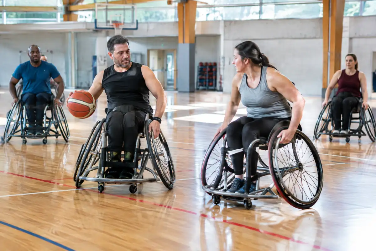 Séance de basket fauteuil en salle, avec des sportifs qui s’entraînent sur un terrain accessible.
