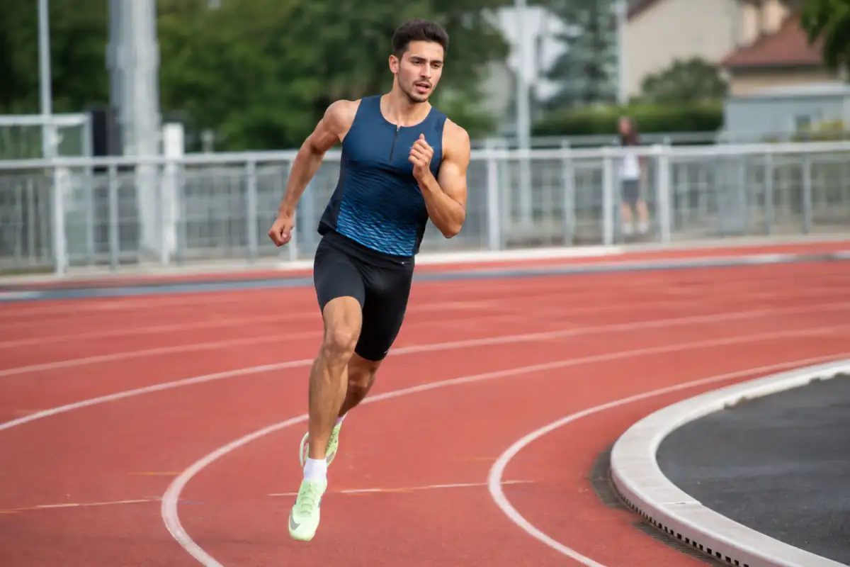 Une athlète sprinte dans son couloir sur le virage d’une piste d’athlétisme lors d’un 400 mètres.