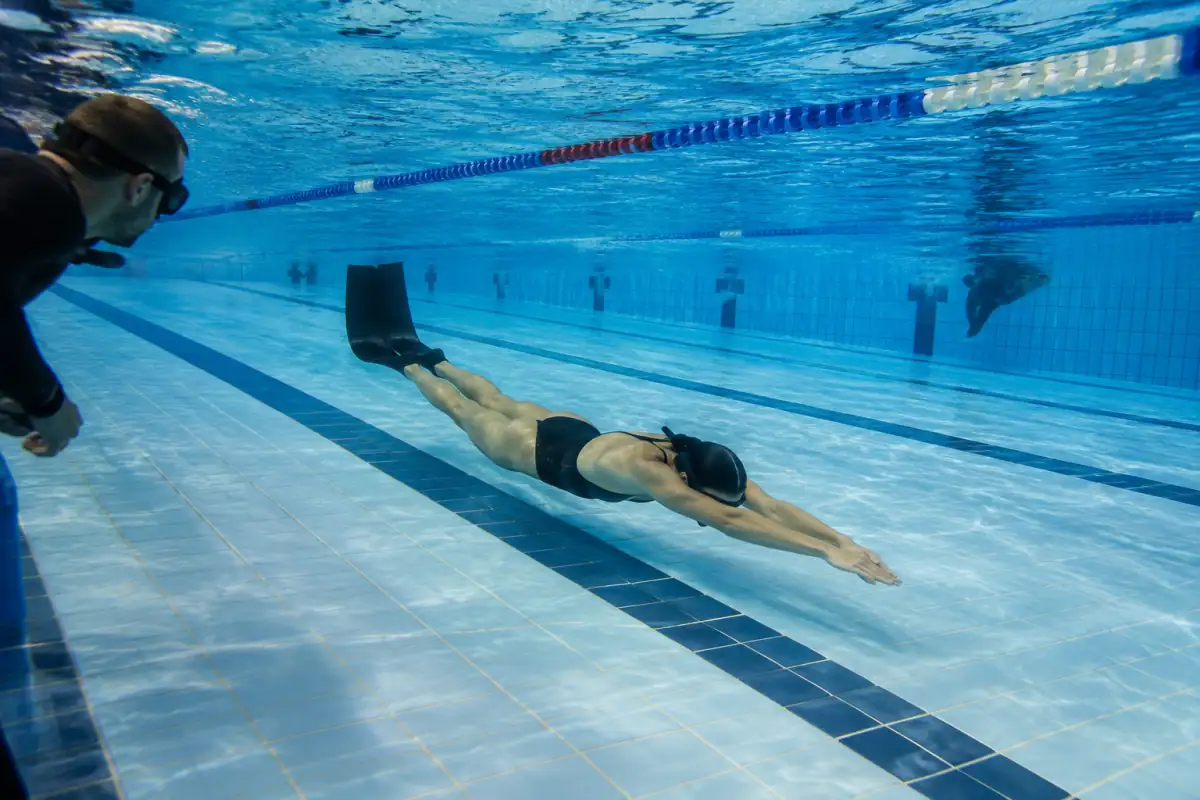Apnéiste en palmes réalisant une longueur sous l’eau lors d’une séance d’apnée vitesse-endurance en piscine.