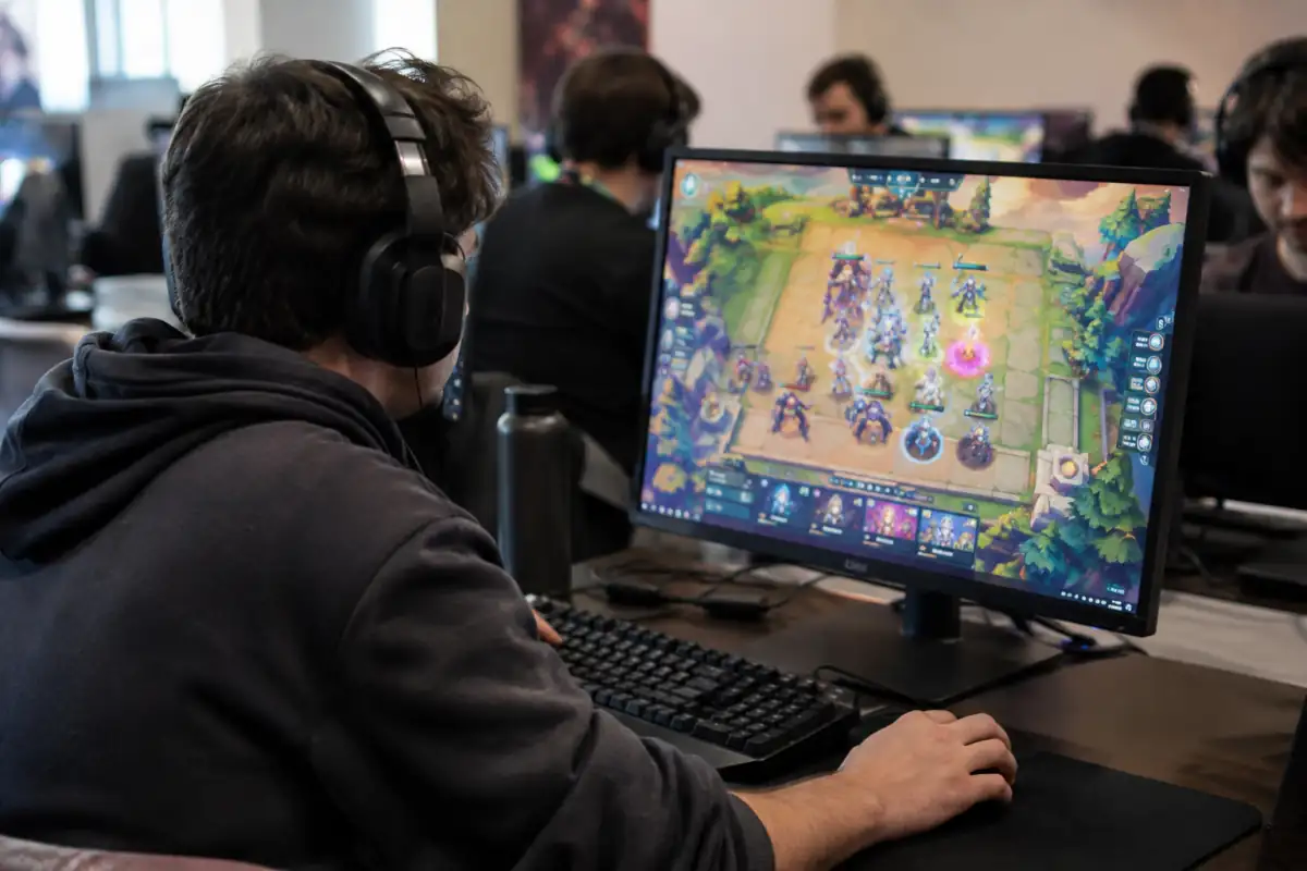 Joueur concentré devant un écran pendant une partie compétitive d’auto-battler, avec des unités virtuelles placées sur un plateau.