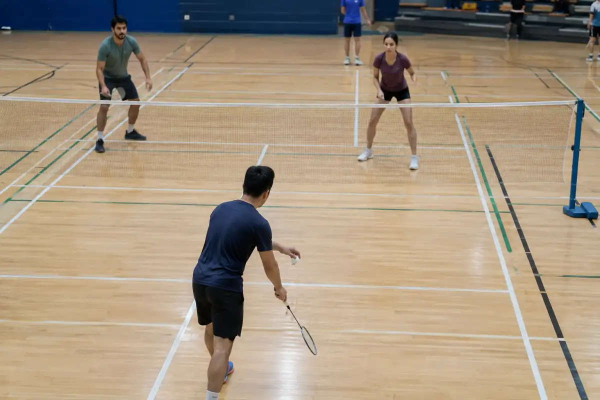 Service en double au badminton : les joueurs se placent en diagonale dans les zones délimitées par les lignes du terrain.