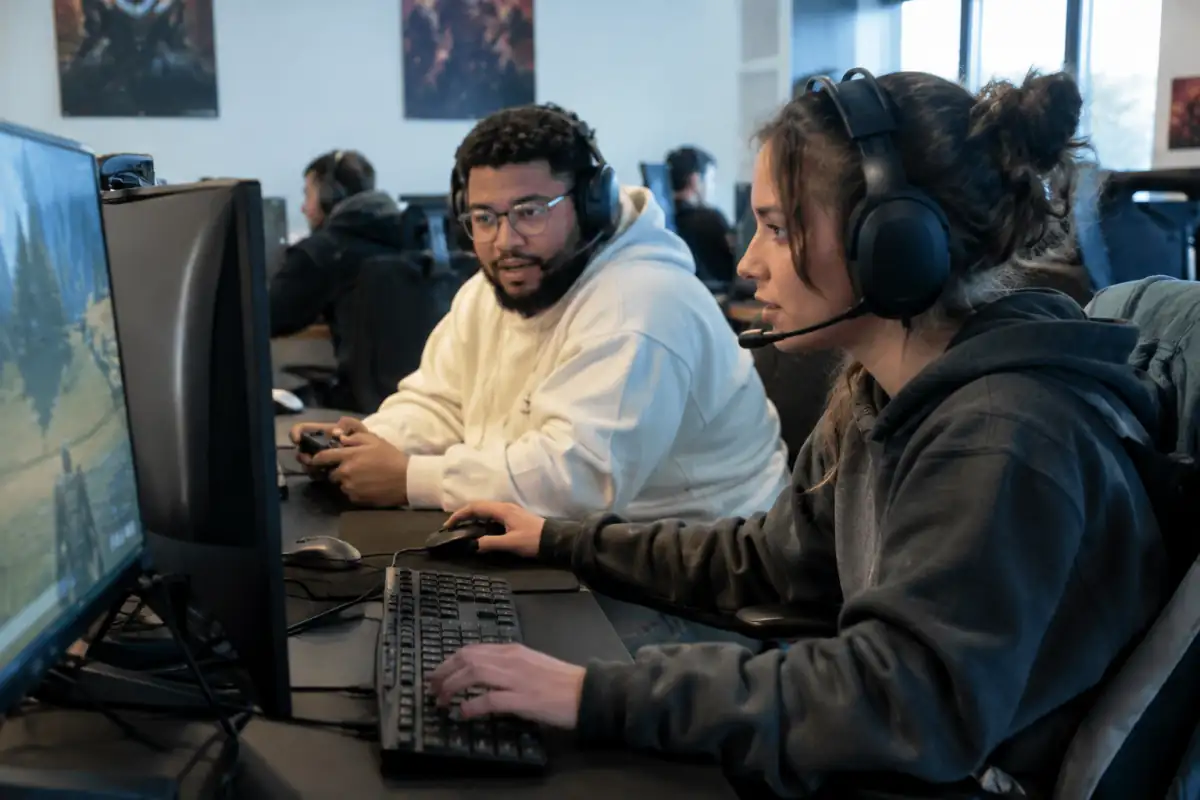 Deux joueurs communiquent au casque pendant une partie de battle royale en e-sport dans une salle de jeu.