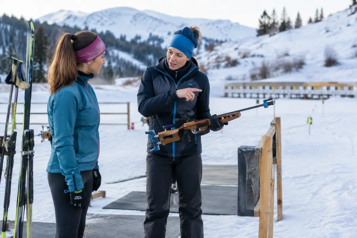 Un débutant écoute les consignes de sécurité d’un encadrant avant une séance découverte de biathlon en club.