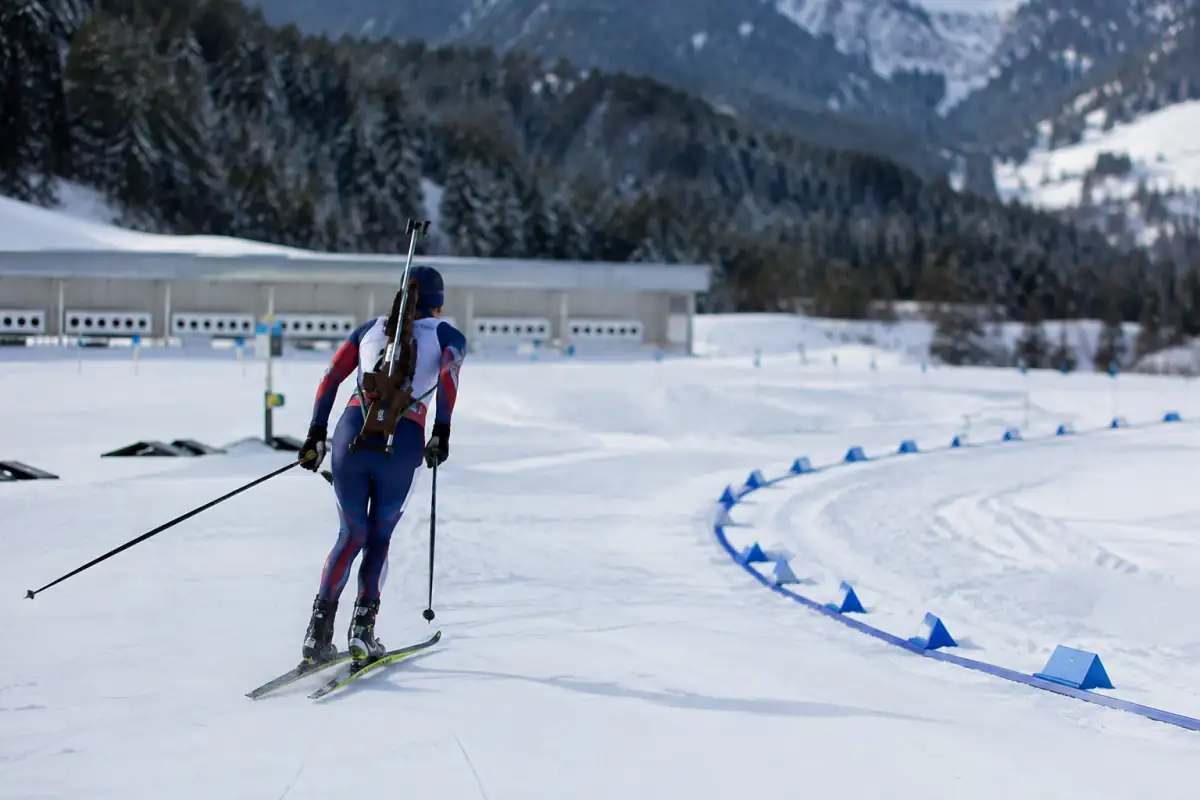 Biathlète quittant le pas de tir pour parcourir la boucle de pénalité après une cible manquée, sur un stade enneigé.