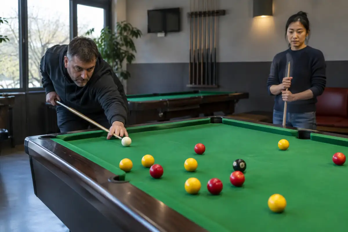 Un joueur vise la bille blanche sur une table de billard chinois à huit, entourée de billes rouges, jaunes et noire.