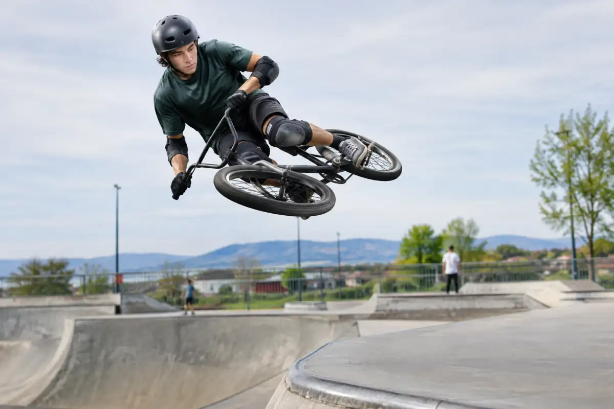 Un pilote de BMX freestyle réalise un tabletop au-dessus d’une rampe de skatepark, avec casque et protections.