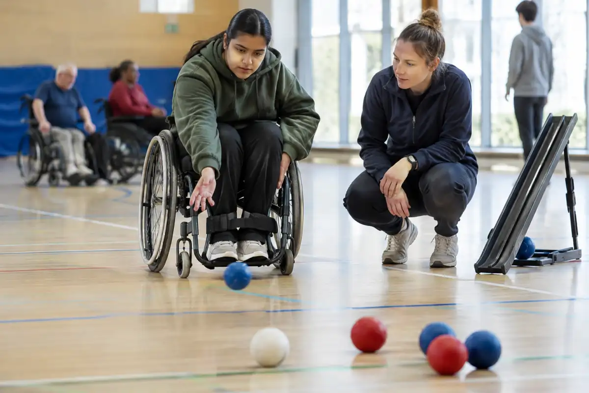 Une personne en fauteuil roulant lance une balle de boccia pendant une séance d’essai dans un gymnase accessible.