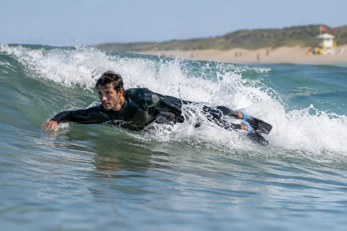 Bodysurfeur en combinaison et palmes glissant sans planche sur une petite vague de l’Atlantique.