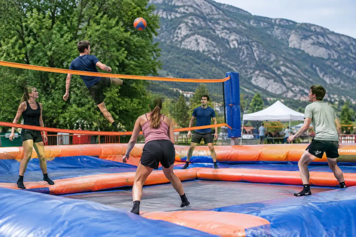 Joueurs de bossaball disputant un échange au pied et à la main sur une structure gonflable avec trampoline et filet.