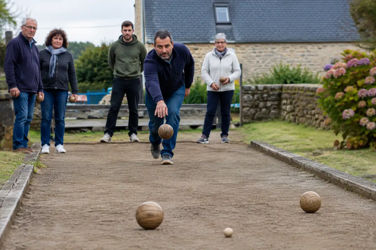 Joueur lançant une boule bretonne lestée sur un terrain de terre, avec le petit but posé à proximité.