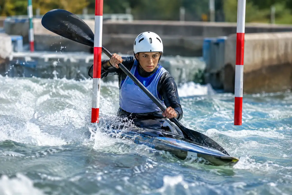 Pagayeur en kayak franchissant une porte amont rouge sur un bassin d’eau vive lors d’une séance de canoë-kayak slalom.