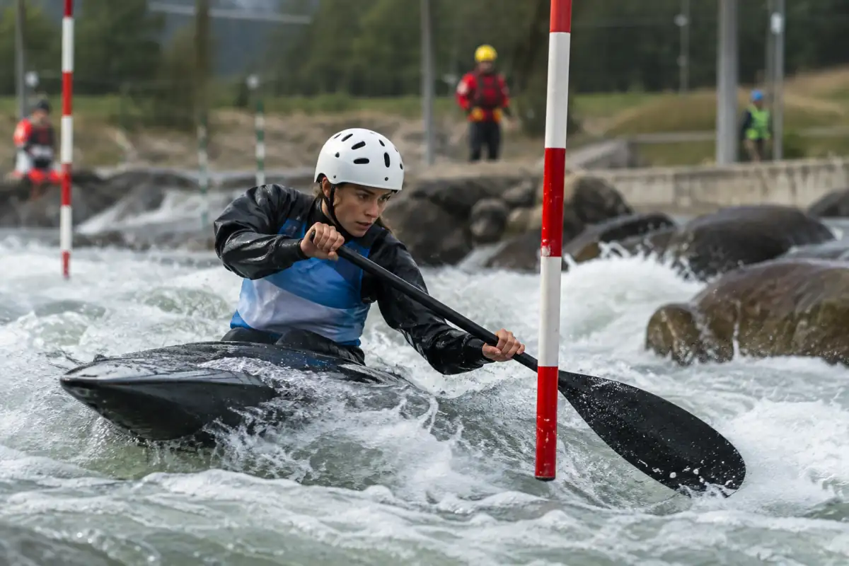 Un kayakiste franchit une porte rouge à contre-courant sur un parcours de slalom en eau vive.