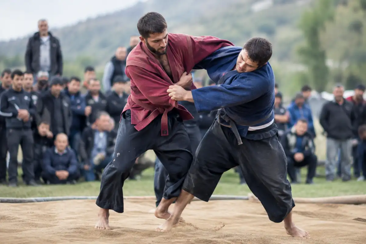 Deux lutteurs en veste traditionnelle géorgienne s’affrontent debout en chidaoba lors d’une tentative de projection.