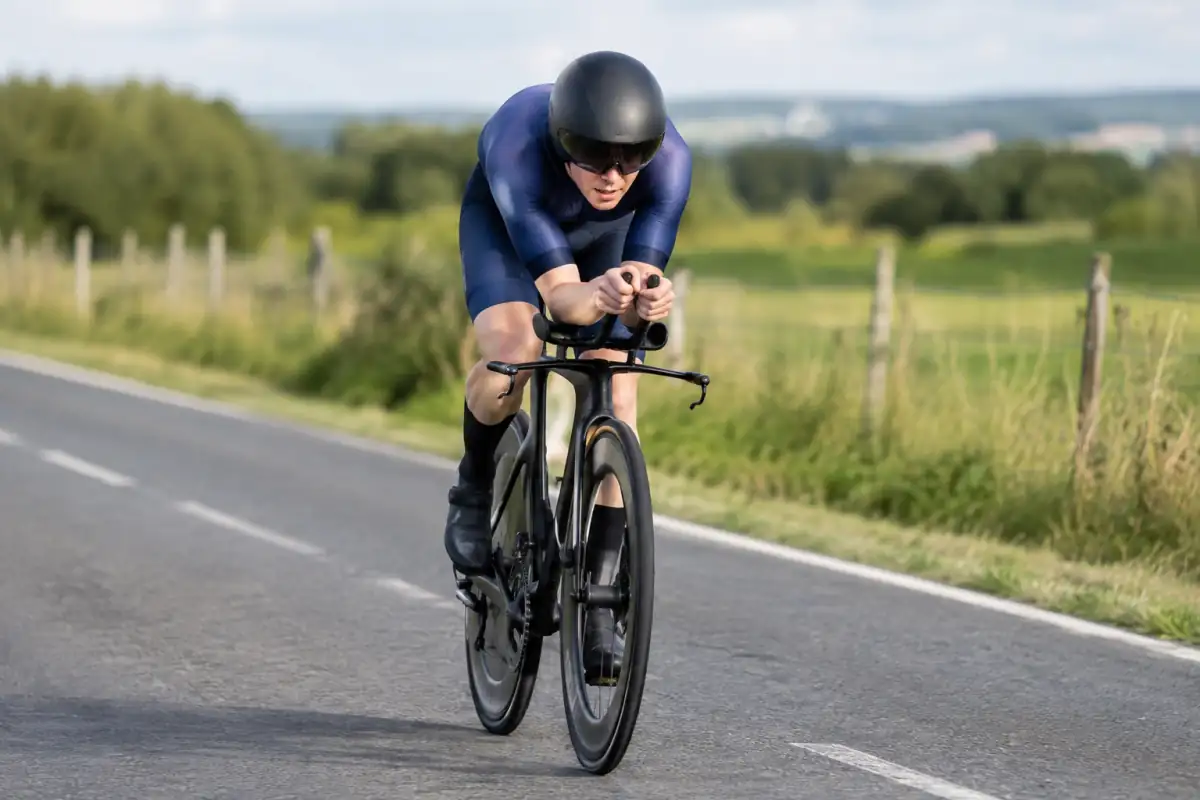 Cycliste en position aérodynamique sur un vélo de contre-la-montre lors d’une épreuve sur route.