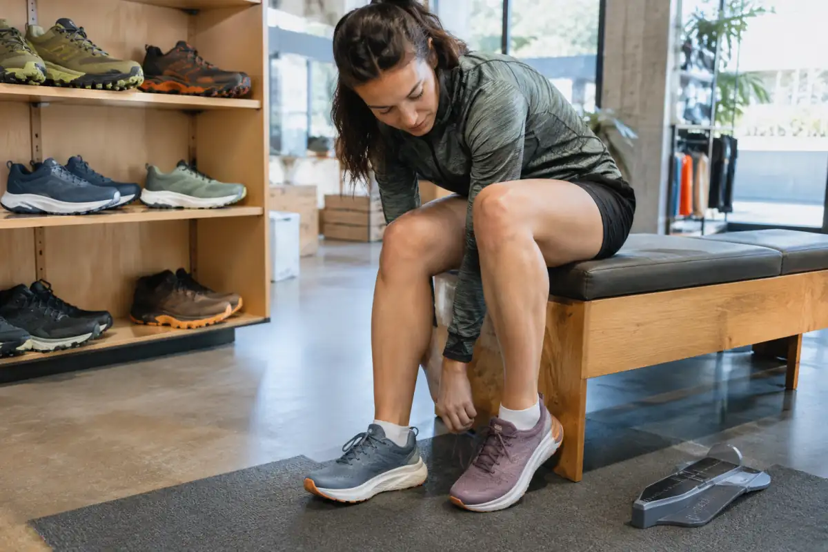 Une personne débutante essaie des chaussures de running en magasin et vérifie l’espace devant les orteils et le maintien du talon.