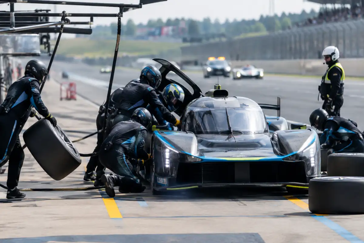 Arrêt aux stands d’une course d’endurance : mécaniciens coordonnés autour d’une voiture pendant un relais et un changement de pneus.