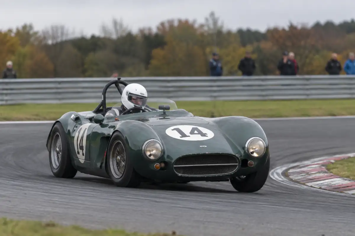 Une voiture GT de course des années 1960 négocie un virage sur circuit lors d’une épreuve de course automobile historique.