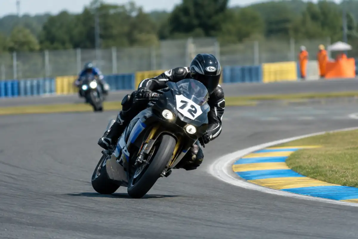 Pilote en combinaison de cuir négociant un virage sur une moto équipée pour une course d’endurance sur circuit.