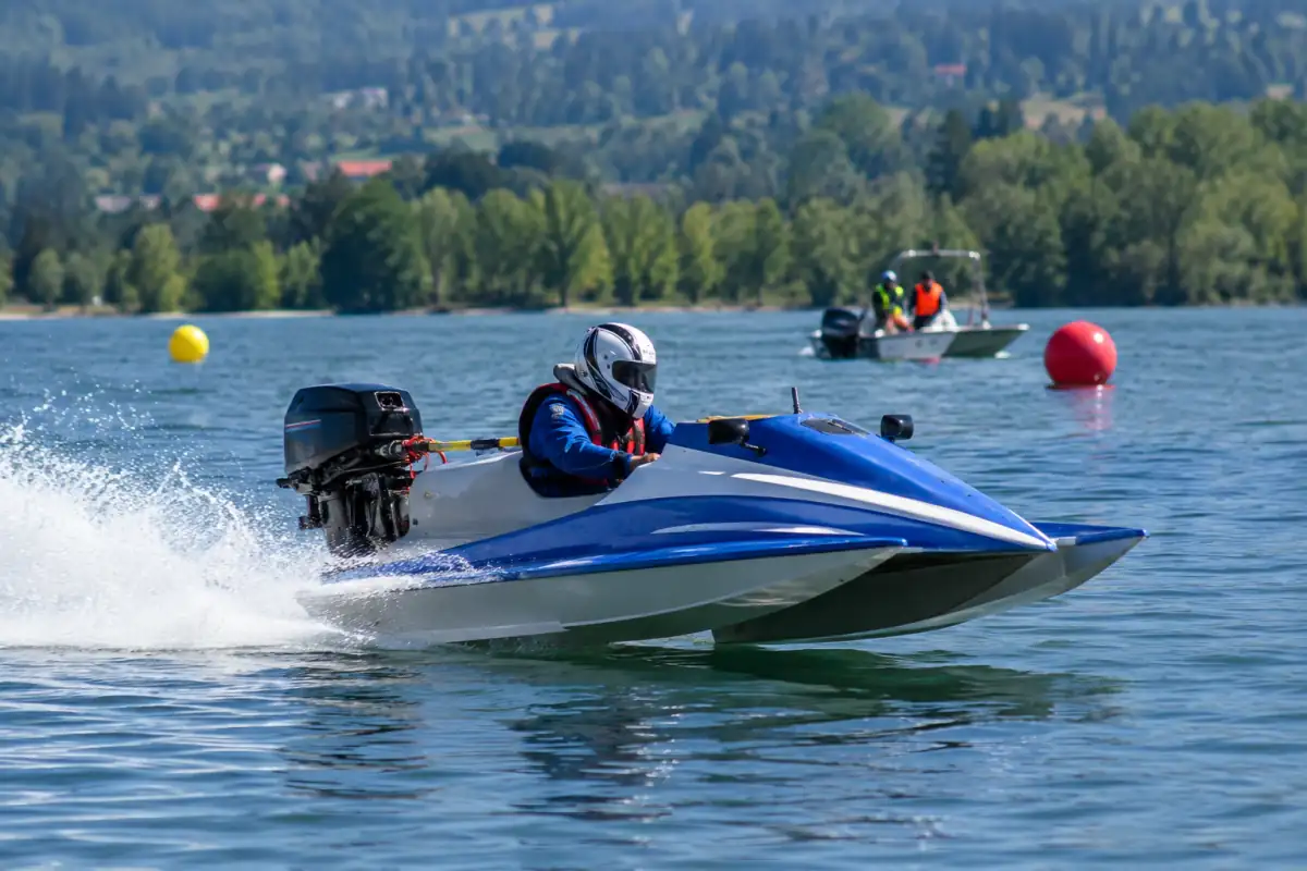 Pilote casqué au volant d’un hydroplane de course qui plane à grande vitesse sur un circuit balisé sur l’eau.