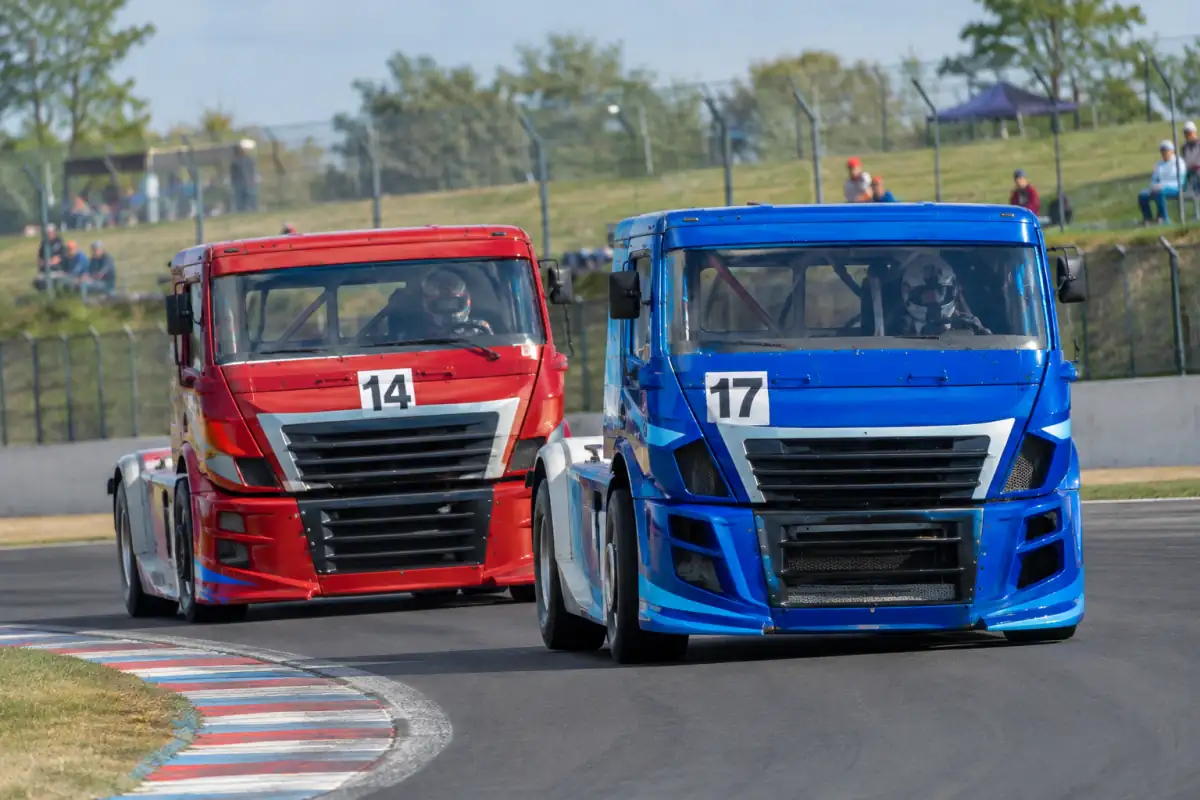 Course de camions sur un circuit français : deux poids lourds de compétition négocient un virage, cabines renforcées et vibreurs visibles.