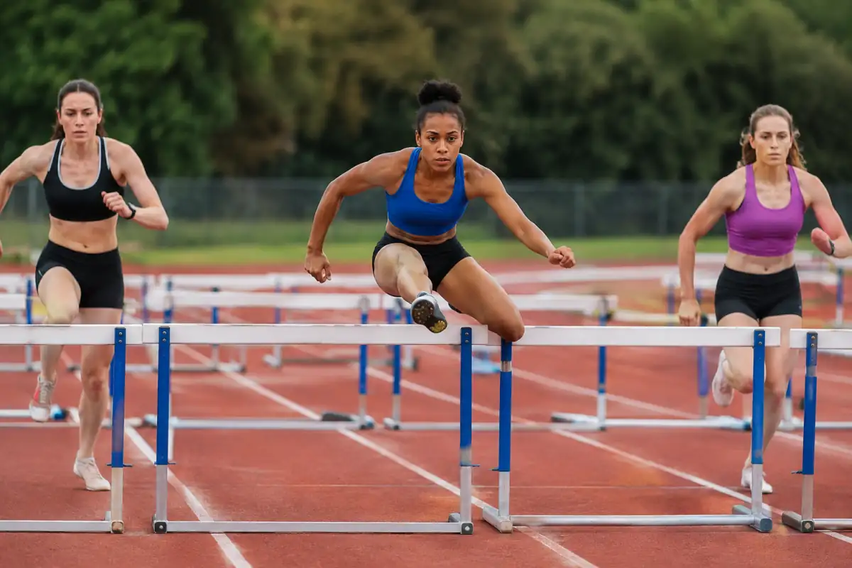 Des athlètes franchissent des haies dans leurs couloirs sur une piste d’athlétisme, lors d’une course réglementaire.