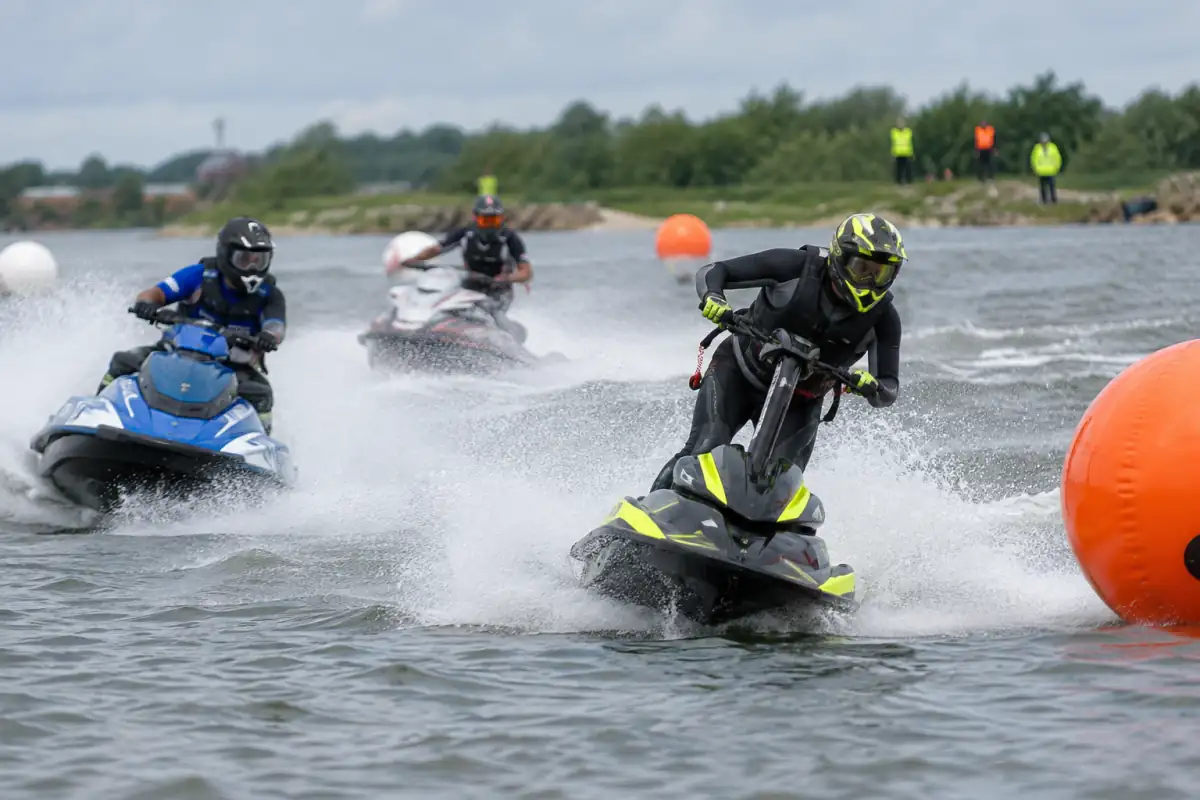 Course de jet-ski : des pilotes en motomarines négocient une bouée sur un circuit balisé, équipés de casques et de gilets.