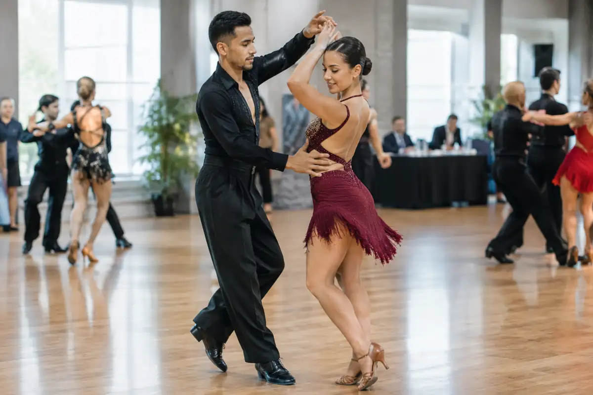 Un couple exécute un pas de bachata sur le parquet d’une salle pendant une compétition de danse.