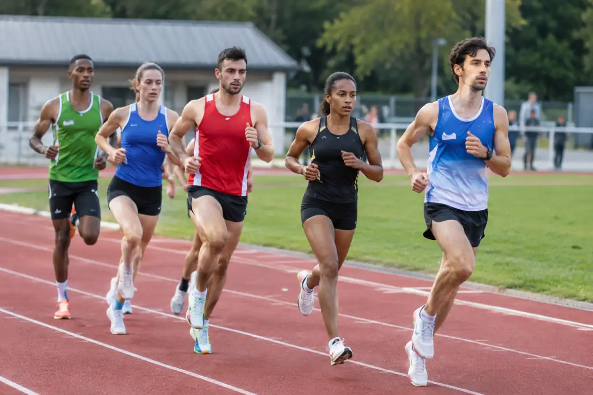 Coureurs de demi-fond en peloton disputant un 1 500 m sur une piste d’athlétisme extérieure.