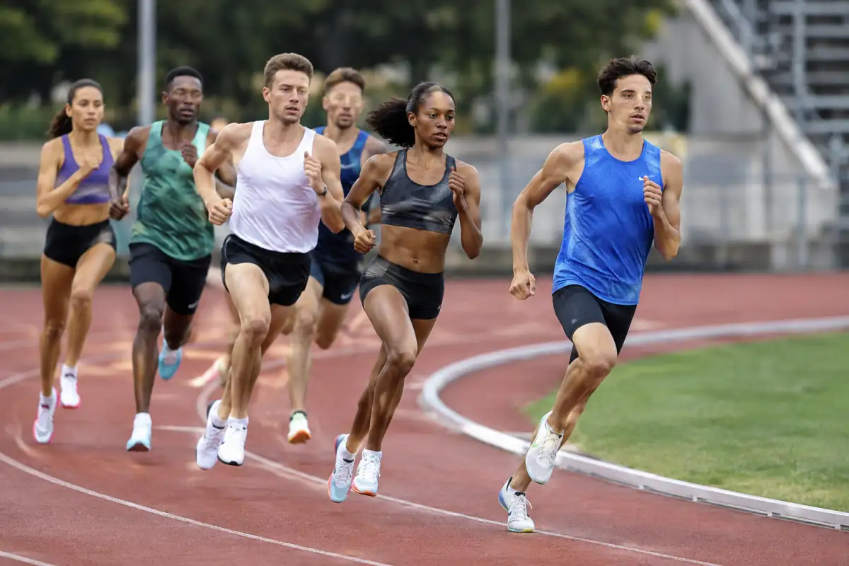 Coureurs de demi-fond placés dans un virage, avec un athlète qui dépasse proprement sans contact sur la piste.