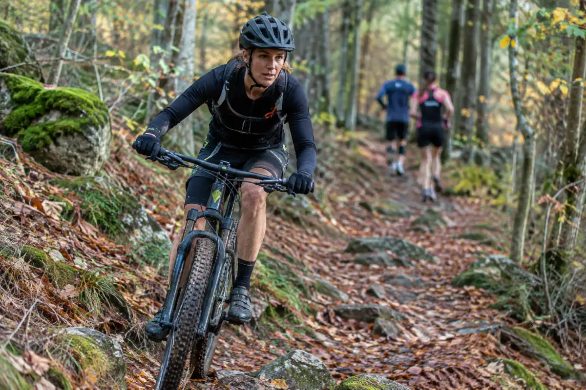 Un athlète en VTT franchit un sentier forestier lors d’une épreuve de duathlon cross, entre les deux courses à pied.