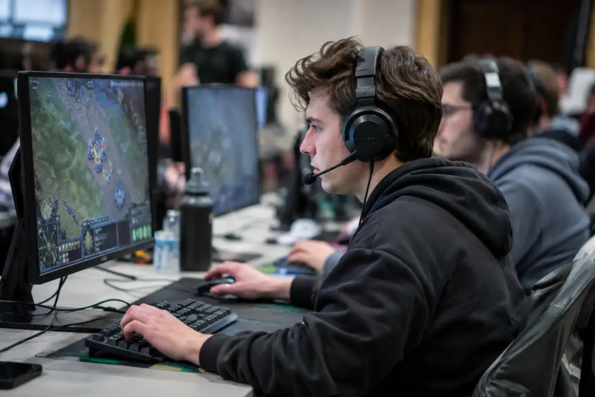 Joueur concentré sur un jeu de stratégie en temps réel lors d’une compétition d’e-sport, avec souris, clavier et casque.