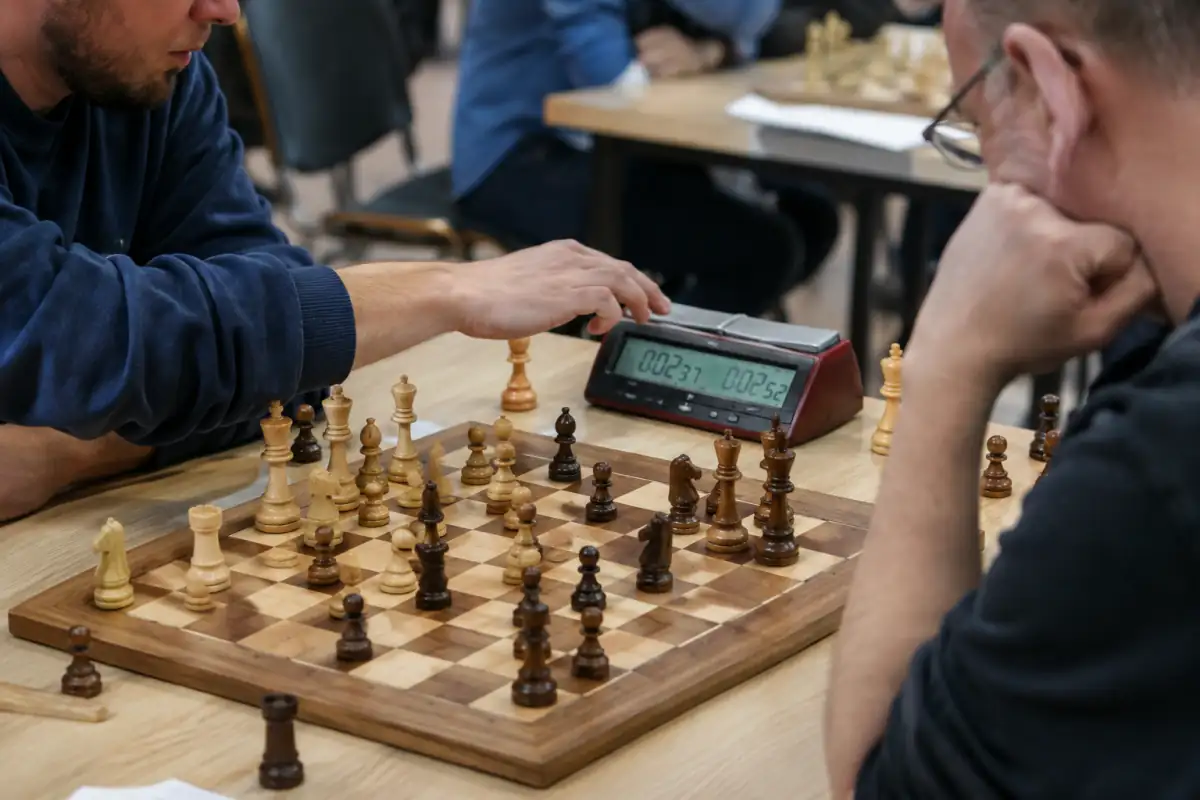 Un joueur de blitz vient de déplacer une pièce et appuie sur son côté de la pendule numérique avec la même main.