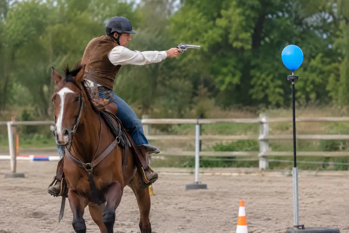 Équitation de tir monté : un cavalier en tenue western suit un parcours extérieur et vise une cible gonflable à cheval.