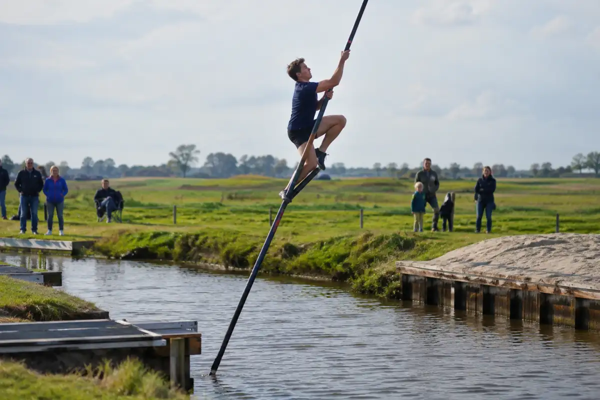 Un athlète grimpe à la perche au-dessus d’un canal lors d’un saut de fierljeppen en Frise.