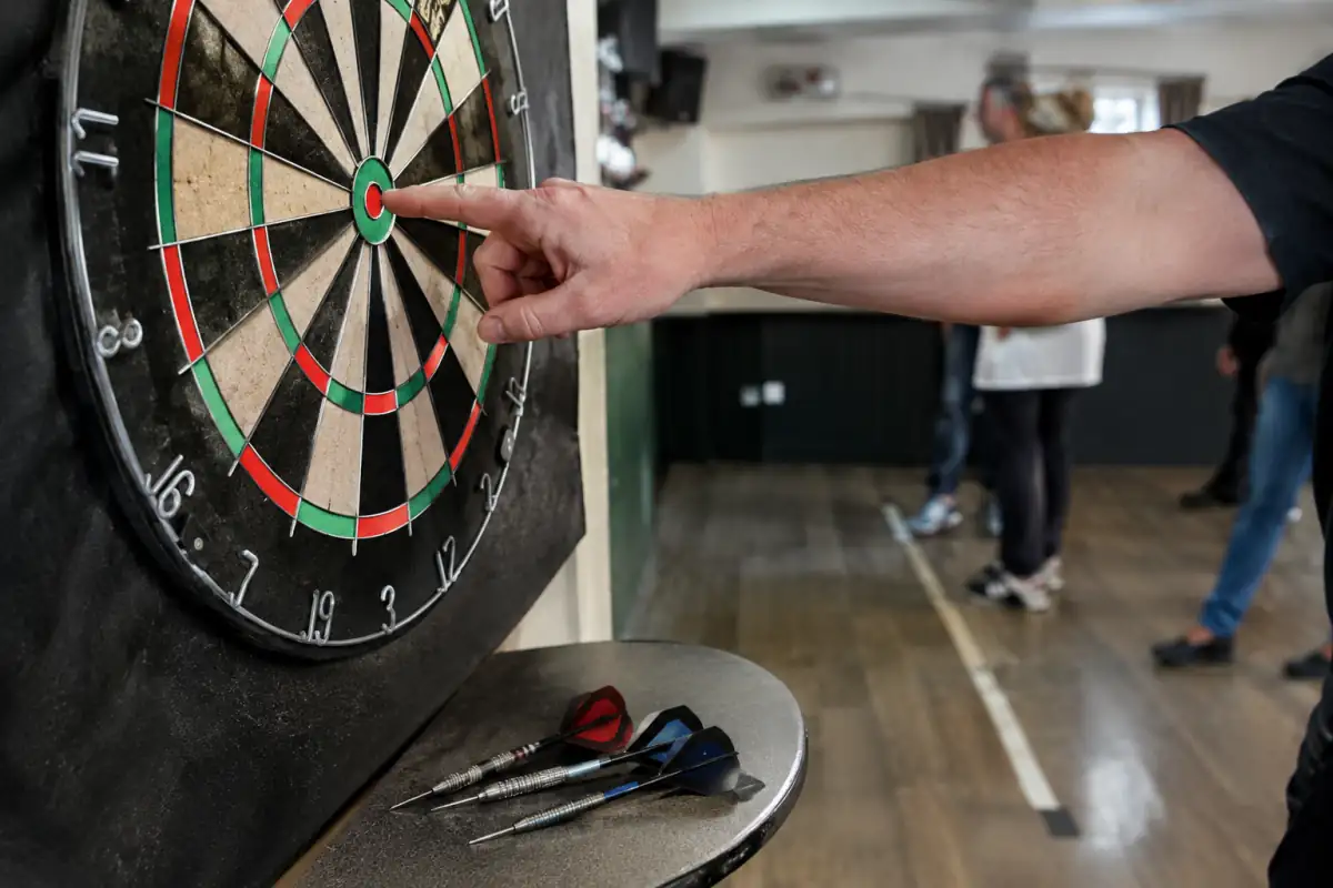 Gros plan sur une cible de fléchettes montrant le bull, les anneaux de score et les éléments d’une fléchette.