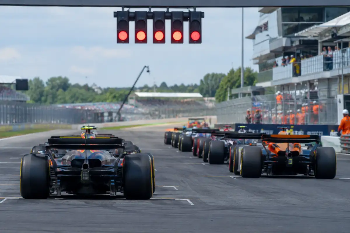 Monoplaces de Formule 1 alignées sur la grille sous les cinq feux rouges avant le départ d’un Grand Prix.