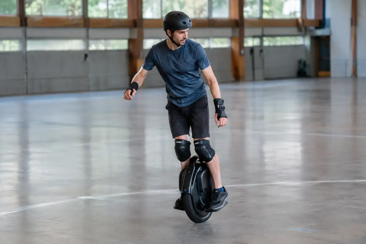 Séquence de freestyle en monoroue électrique : un pratiquant casqué réalise un pivot lent sur sol lisse dans une salle dégagée.