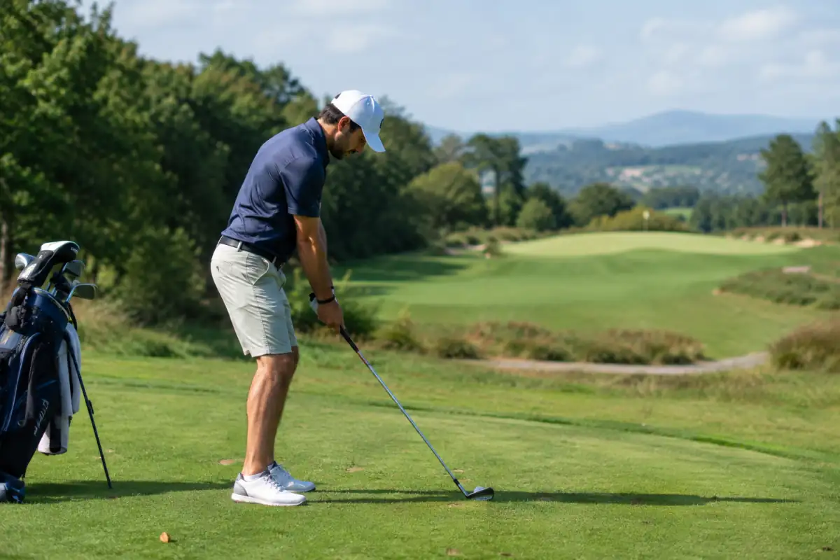 Joueuse de golf en plein swing sur un parcours, un fer en main et le fairway français en arrière-plan.