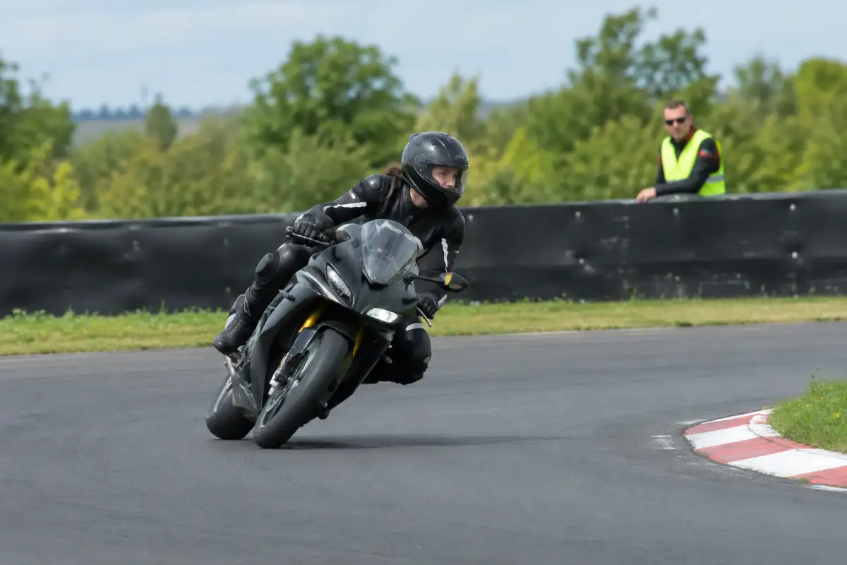 Pilote débutant sur circuit, regard porté vers la sortie du virage, buste décalé et mains détendues sur une moto sportive.