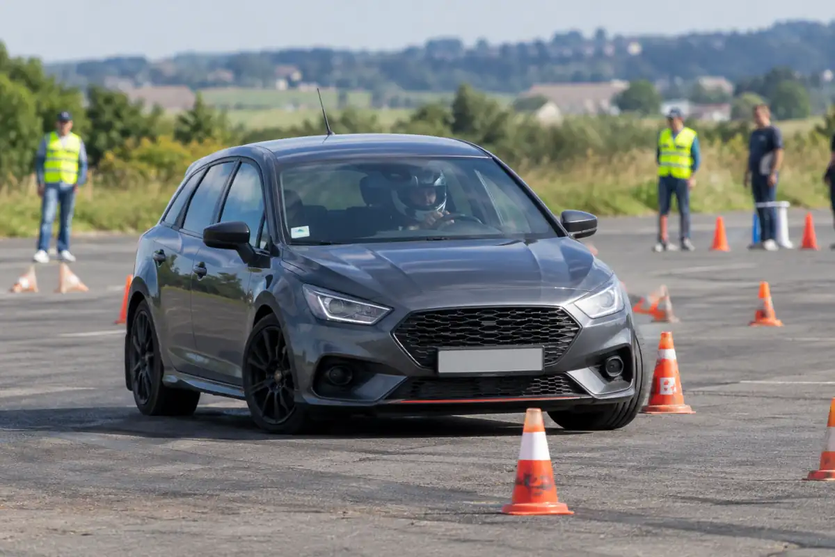 Une voiture négocie un slalom de cônes lors d’une séance de gymkhana automobile sur une piste fermée.
