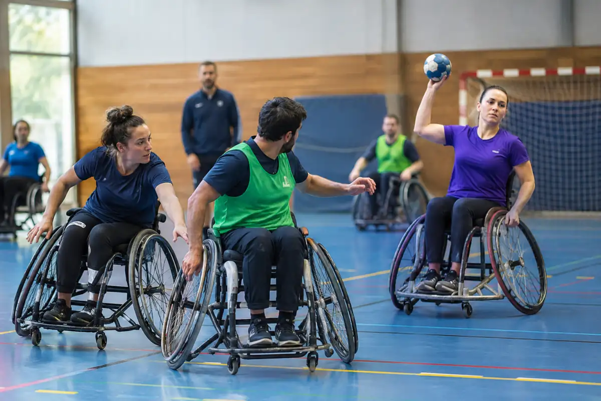 Des joueurs en fauteuil de sport se disputent le ballon pendant une séance de handball fauteuil dans un gymnase.