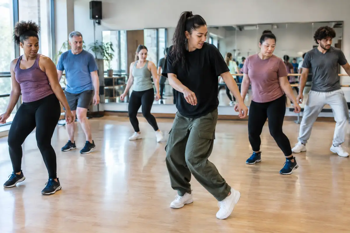 Un professeur montre un pas simple à un groupe d’adultes débutants pendant un cours de hip-hop chorégraphique en studio.