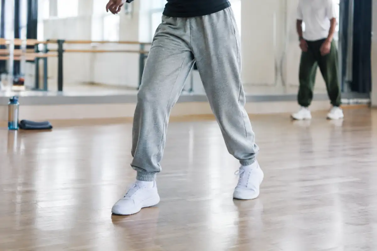 Baskets propres et pantalon souple pendant un test de pas latéraux dans un studio de hip-hop.